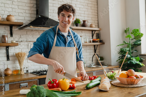 Fényképezés Happy young Caucasian chef man enjoying cooking hobby in contemporary home kitch