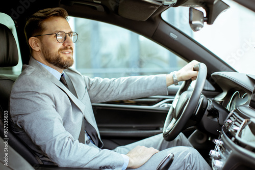 Business professional driving a car in formal wear during the day in an urban area