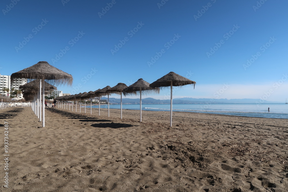 Fototapeta premium Sun Umbrellas Lined Up on Benalmádena Beach, Costa del Sol, Spain