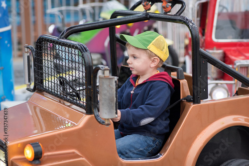 Little boy riding on a tiny vehicle at an amusement park
