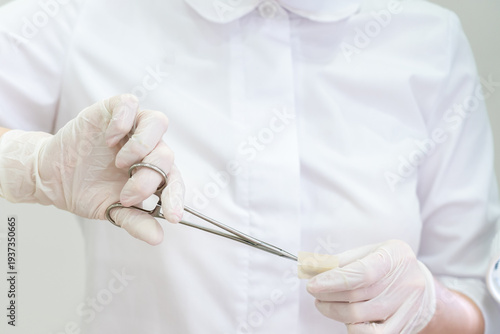 Foto Doctor wearing gloves using a surgical forceps to open band aid