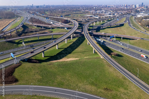 Aerial of. intricate landmark highways crossing each other at Voorburg intersection transit in Dutch landscape with cityscape of The Hague. Infrastructure and urban transportation