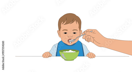 A baby with brown hair and a blue bib sits at a white table being spoon-fed white food by an adult's hand.