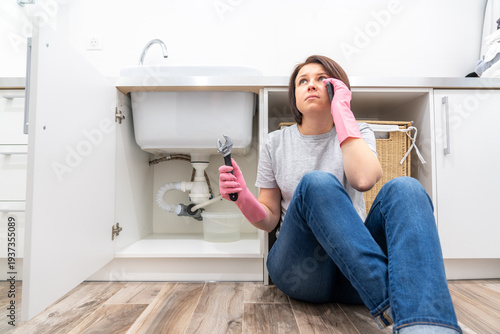 Εκτύπωση καμβά Woman sitting near leaking sink in laundry room calling for help
