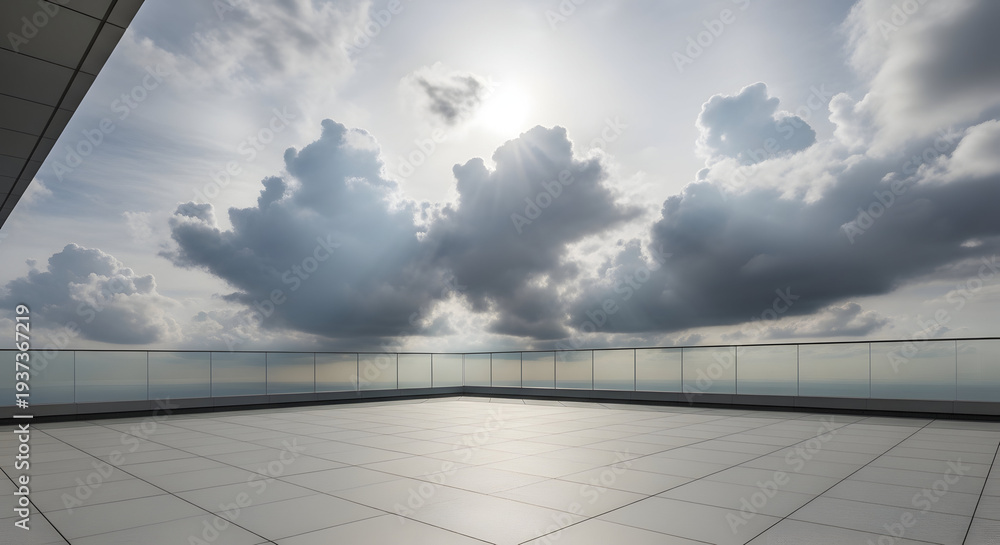 Obraz premium Expansive rooftop terrace with modern glass railings overlooking a dramatic cloudy sky and distant horizon, bathed in sunlight