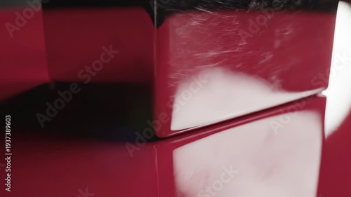 Abstract close-up of two red-gloss surfaces; light and shadow play. Focus on reflective surfaces