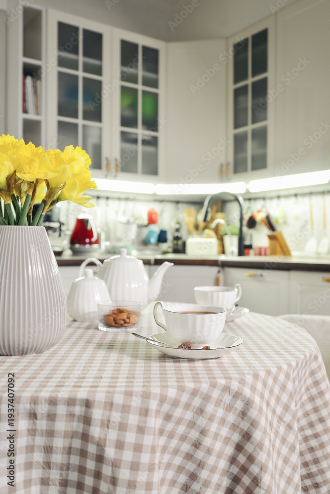 Fototapeta premium A table set for breakfast with tea and a bouquet of daffodils