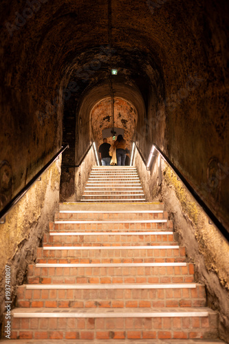 Visit of deep and long underground caves tunnel and stone bricks staircase, traditional method making champagne sparkling wine in Reims, Champagne, France