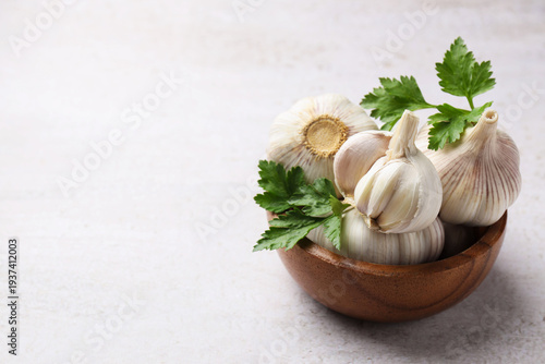 Fresh garlic and parsley on light grey table, closeup. Space for text