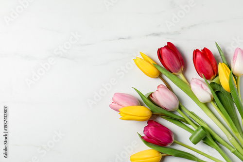 Beautiful colorful tulip flowers on white marble background, flat lay. Space for text