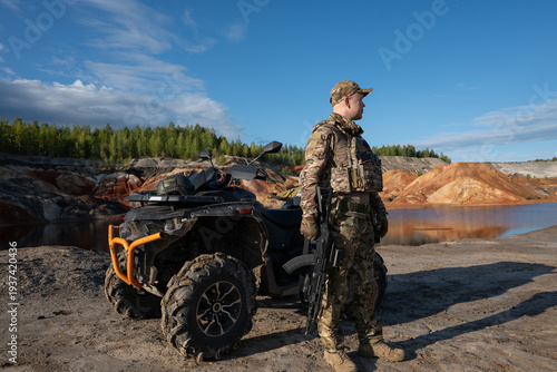 Armed Soldier Standing Near ATV in Rugged Quarry Landscape