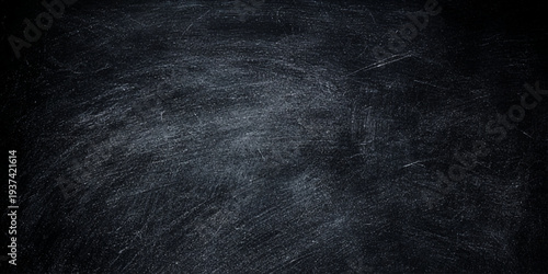 Dark blue grunge chalk texture on an old black chalkboard surface with a rough vintage material pattern for a blank textured wallpaper backdrop