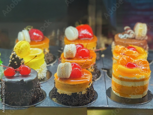 Assortment of dessert cakes displayed in pastry shop showcase with fruit topping chocolate glaze, macarons. Dessert selection bakery products sweet food display for cafe menu, confectionery business
