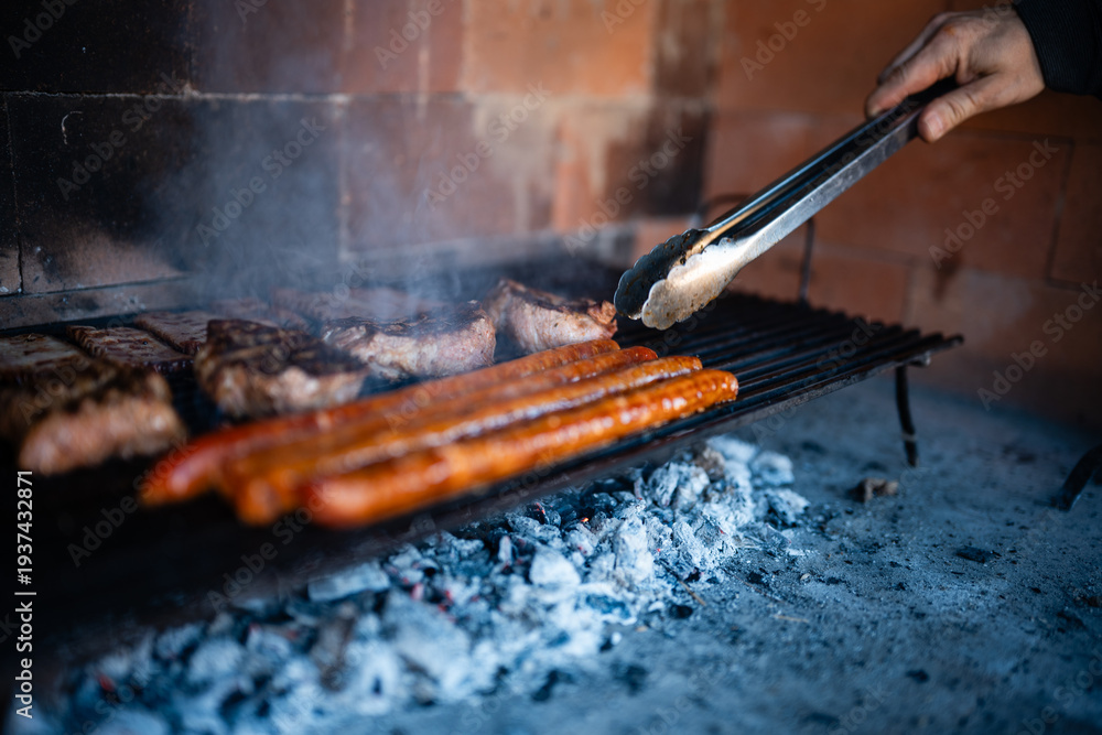 Naklejka premium Hand grilling meat and sausages on hot charcoal