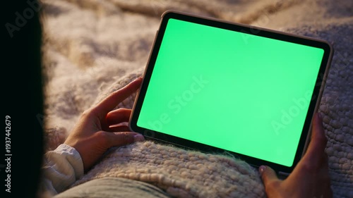 Woman hand holding mockup tablet lying bed closeup. Lady watching online video