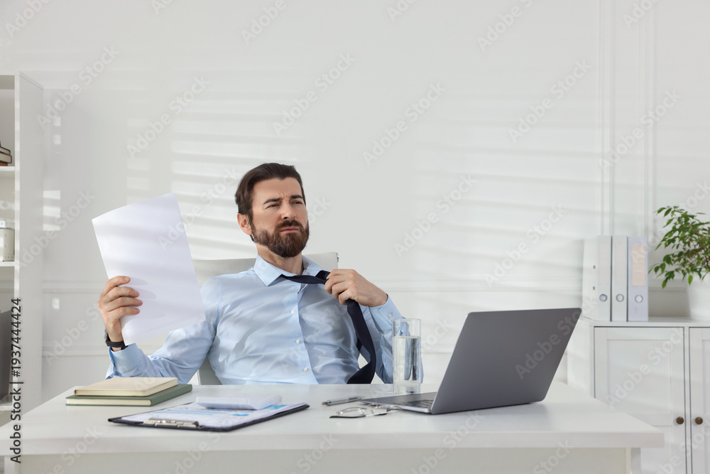 Fototapeta premium Man suffering from heat at table near white wall indoors, space for text