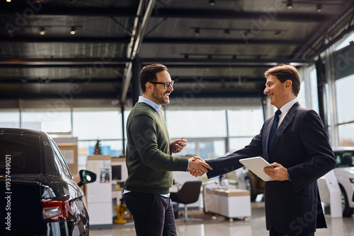 Canvastavla Happy man shaking hands with salesman after buying new car in auto salon