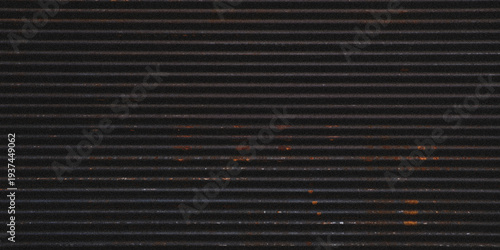 фотографія Dark corrugated metal with scattered small orange and brown rust spots