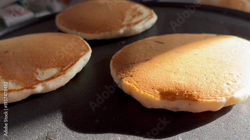 Close-up of golden brown pancakes cooking on a hot pan, with a crispy edge. Perfect for food preparation, breakfast cooking, and food content creation.