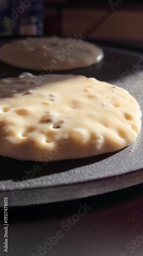 Close-up footage of pancake batter cooking in a hot pan, showing bubbles forming. Perfect for cooking tutorials, food preparation, and breakfast-related content.