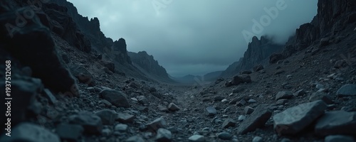 Barren rocky canyon with sharp peaks and cloudy sky. Dark, desolate wasteland with stony ground. Vast, empty valley under moody atmosphere. Cosmic, alien terrain.