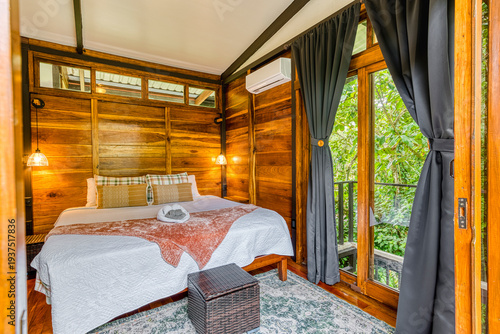 Cozy cabin bedroom with wooden walls and tropical view