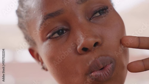 black woman influencer making kissy faces closeup, radiant skin with dew, braided hair, playful smile and cheek gesture, skincare and beauty content vibe for social media trend videos
