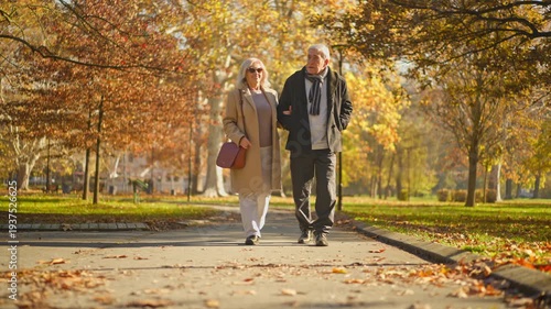 Elderly couple walking arm in arm through a park during autumn with colorful leaves