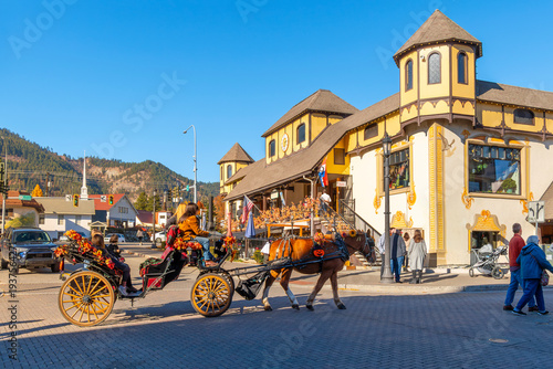 Fotografia Tourists ride in a horse drawn buggy down the picturesque Main Street in the Bavarian themed village of Leavenworth, Washington at Autumn