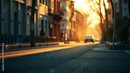 A car drives down a quiet city street at sunset with warm light casting a glow on the buildings and road