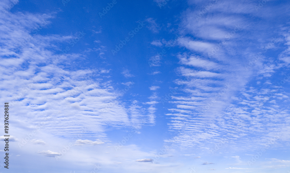 Fototapeta premium Peaceful and serene sky with clouds background. Two layers of cloudiness. Calm abstract sky backdrop. Horizon air gradient and calm sunlight. Blue sky with fluffy clouds wallpaper.