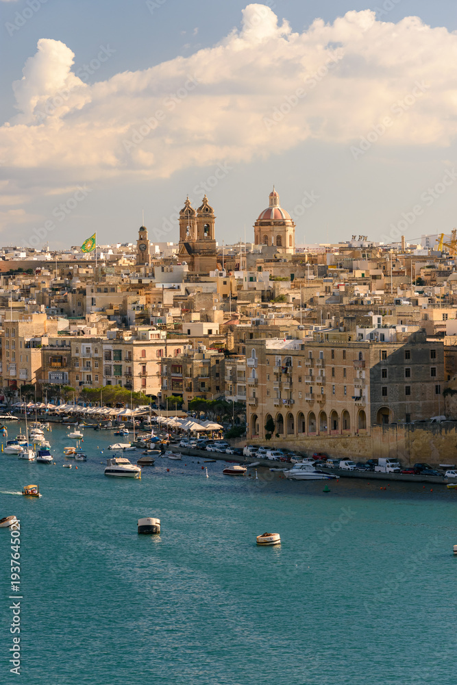 Fototapeta premium Puerto de Birgu (Vittoriosa) en Malta con barcos deportivos y arquitectura histórica al atardecer. Ambiente veraniego mediterráneo.