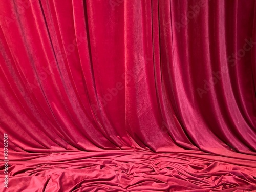 Large red velvet curtains hang high from the ceiling, pooling gracefully on the floor