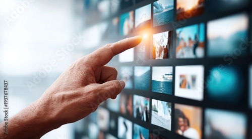 A hand gestures toward a digital screen, selecting an image or interacting with a media interface.