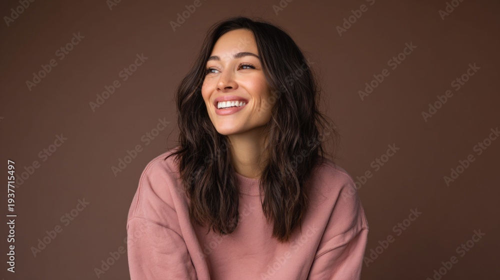 Fototapeta premium Smiling woman with long dark hair looking away, wearing a pink sweater