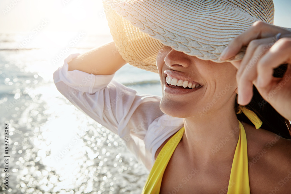 Fototapeta premium Beach, smile and woman with hat for vacation, summer holiday and safety in nature on adventure. Cover, ocean and happy person with accessory outdoor for calm, relax and protection on weekend trip