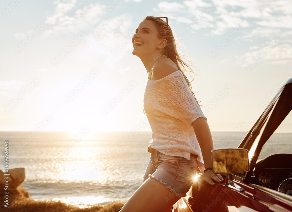 Fototapeta premium Laugh, road trip and woman by car by ocean for relax, vacation or weekend with outdoor break. Sunset, sea water and female person by convertible vehicle for holiday, adventure or travel in summer.