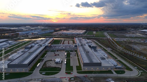 Expansive aerial view orbiting around a large, modern data center complex at sunset