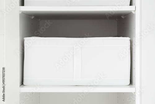 White textile storage shelf case for clothes and other things in opened wardrobe at home room. Closeup. Front view.