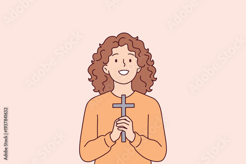 Curly haired young woman praying with a religious cross in her hands to find spiritual hope and express her christian faith during easter holy week