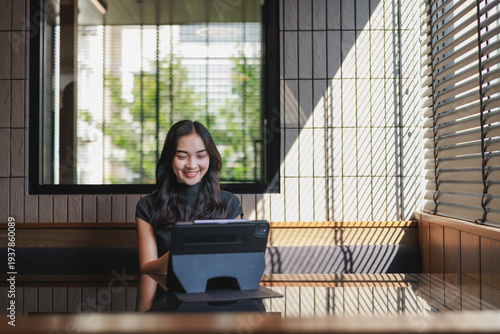 Young woman smiling while working with tablet in modern cafe