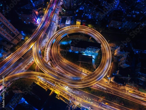 Aerial view of a stunning urban highway interchange at night, showcasing intricate road networks and vibrant light trails.