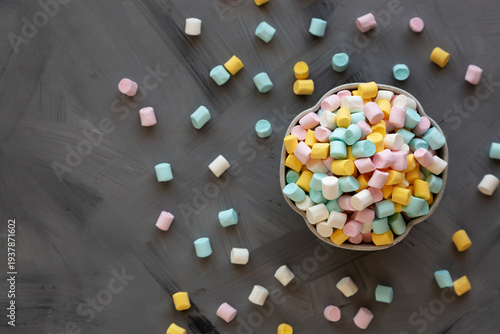 Unhealthy multi-colored mini marshmallows in a bowl, top view.