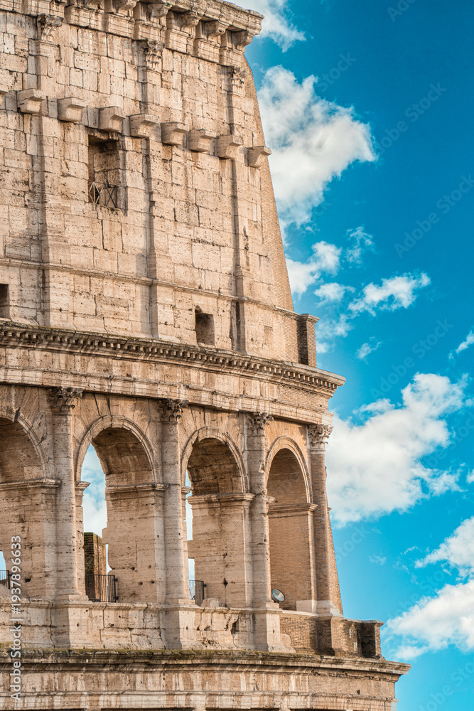 Obraz premium Famous Roman Colosseum, an ancient amphitheater and UNESCO world heritage site, glowing under the warm sunlight, a testament to imperial Roman architecture and history in Italy