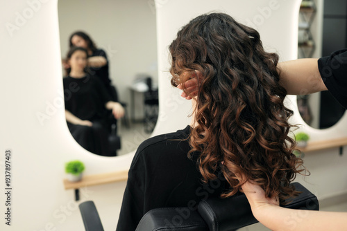 Schilderij op canvas Professional stylist showing perfect curly hair result in a specialized salon mirror