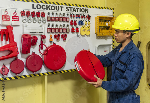 Ship engineer preparing isolation locks at a lockout tagout board as part of safety procedures in maritime operations.