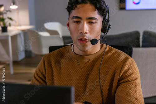 Fényképezés Male support rep wearing brown quilted sweater speaking into headset while viewi