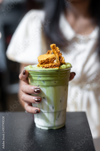 Iced matcha latte layered with milk and topped with crunchy brown sugar waffle pieces