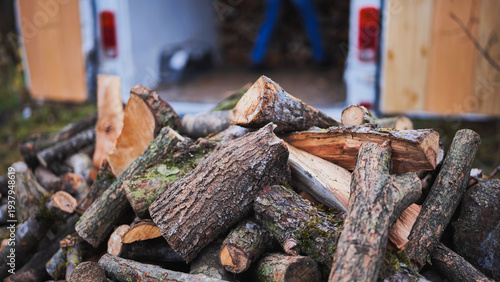 Fotografía A man unloads firewood from a truck by hand.