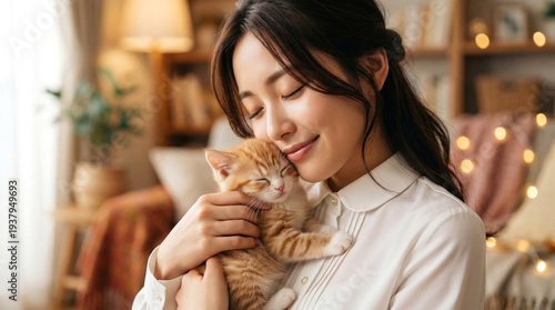 間接照明の柔らかな光の中で子猫を抱き、慈しむように頬ずりする女性